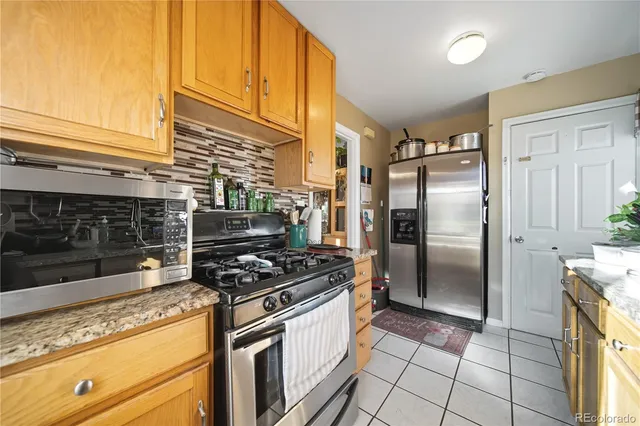 a kitchen with granite countertop a refrigerator and a stove top oven