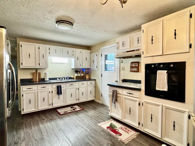 a kitchen with stainless steel appliances granite countertop a stove a sink and white cabinets