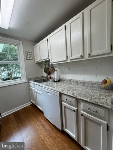 a kitchen with granite countertop wooden cabinets a sink and dishwasher