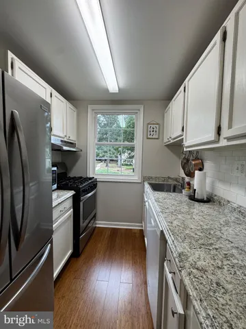 a kitchen with granite countertop wooden floors appliances and sink