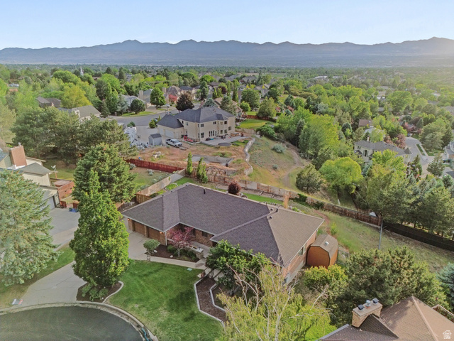 2342 Charros Road Sandy, UT 84092 - Photo 76 of 94 Expansive suburban landscape with a single-story brick residence featuring a multi-car garage, mature front yard landscaping, and a sloped rear yard