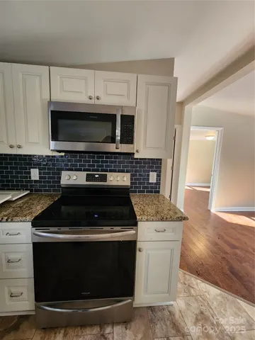 a kitchen with granite countertop a stove and a microwave