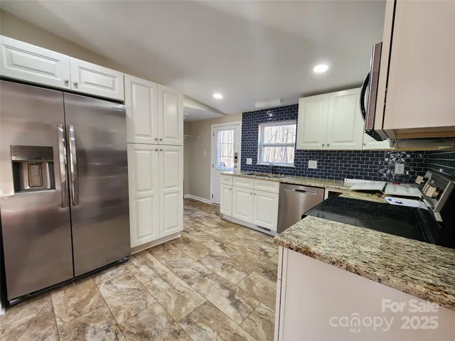 a kitchen with granite countertop a sink a counter top space stainless steel appliances and cabinets