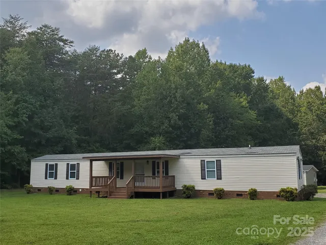 a front view of house with yard and trees in the background