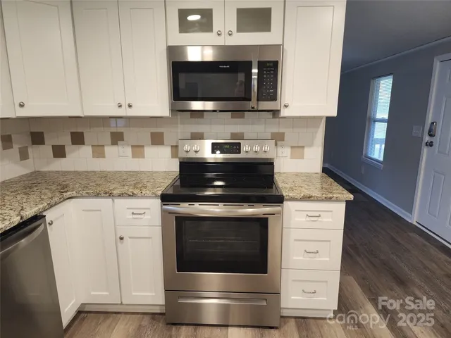a kitchen with granite countertop a stove top oven microwave and cabinets