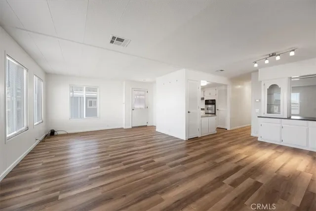 a view of an empty room with window and wooden floor
