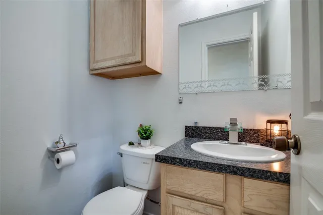 a bathroom with a granite countertop toilet sink and mirror