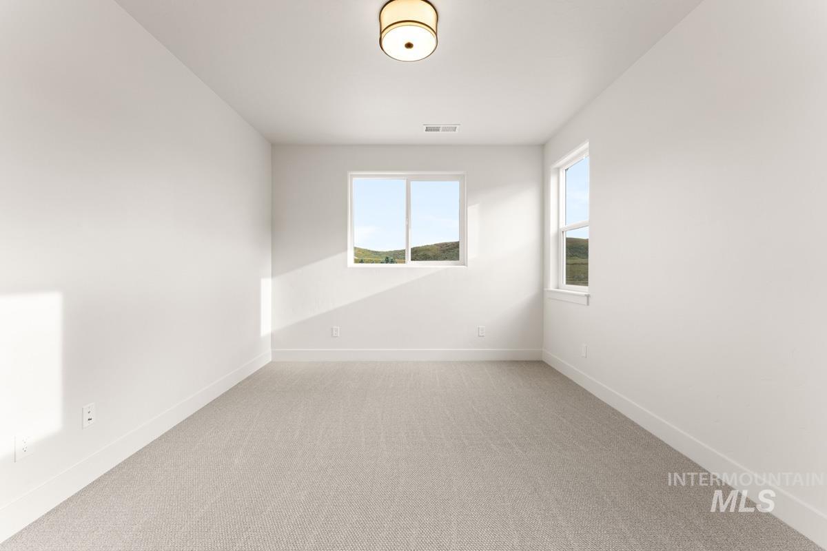 13338 North Spring Creek Way Boise, ID 83714 - Photo 30 of 46 Spacious room featuring neutral carpeting, white walls, and two windows providing natural illumination