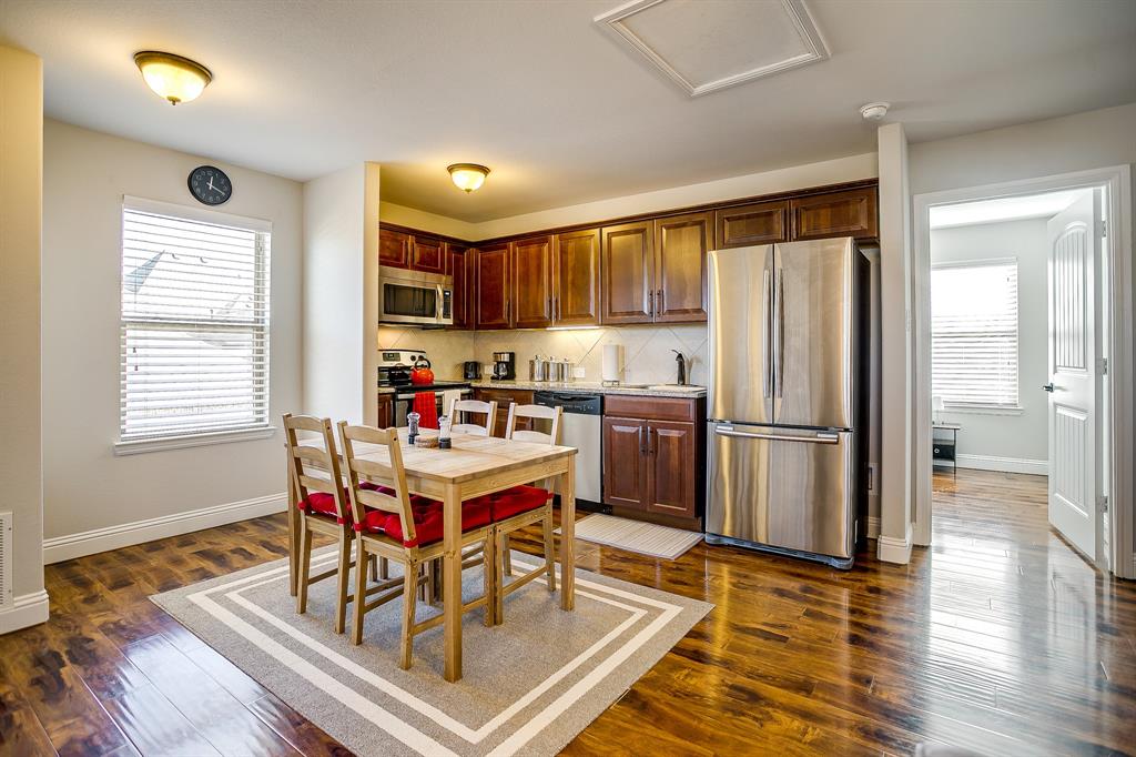 a room with stainless steel appliances a dining table wooden floor and a window