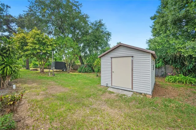 a backyard of a house with table and chairs plants and large tree