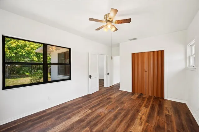 a view of empty room with wooden floor and fan