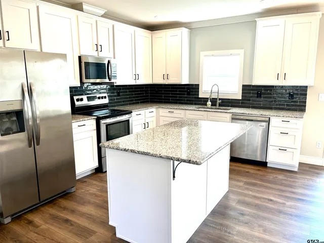 a kitchen with stainless steel appliances granite countertop a stove a sink and a refrigerator