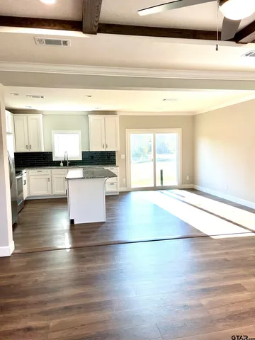 a view of a kitchen with kitchen island a sink wooden floor and a counter top space