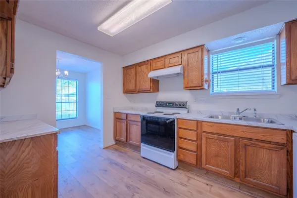 a kitchen with stainless steel appliances granite countertop wooden cabinets a sink a stove a dining table and chairs