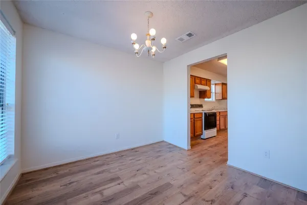a view of a room with wooden floor chandelier and windows