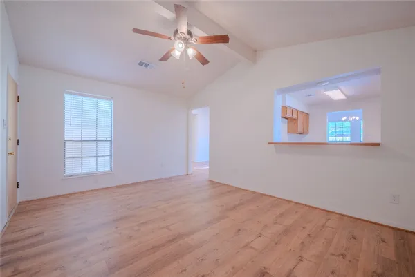 an empty room with wooden floor fan and windows