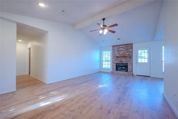 a view of empty room with wooden floor and fireplace