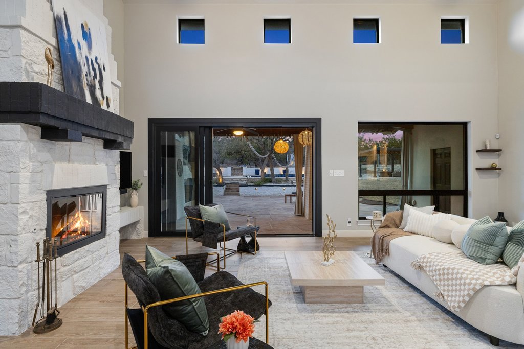 4018 Bee Creek Road Spicewood, TX 78669 - Photo 16 of 40 Light filled living room with fireplace and expansive sliding glass doors.