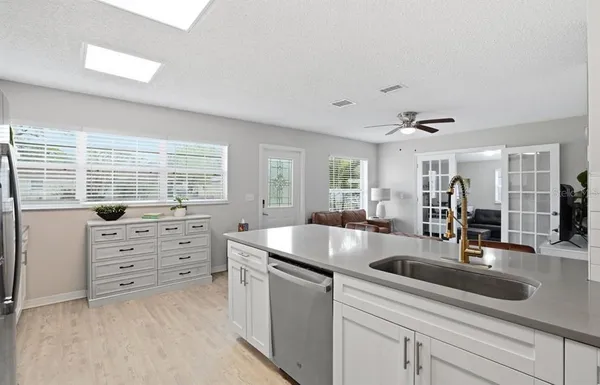 a kitchen with cabinets a sink a counter space and living room view