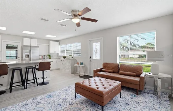 a living room with furniture a rug kitchen view and a large window