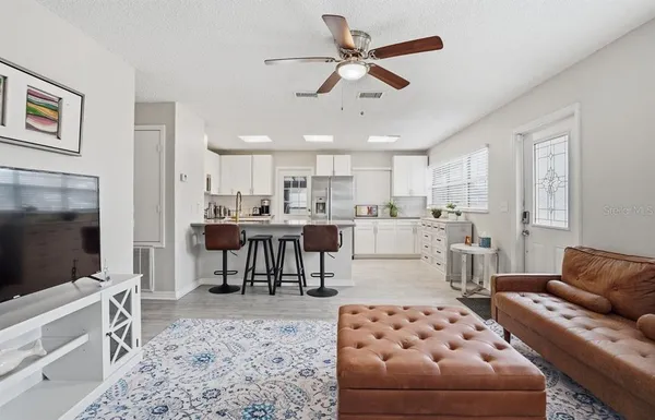 a living room with furniture a flat screen tv and kitchen view
