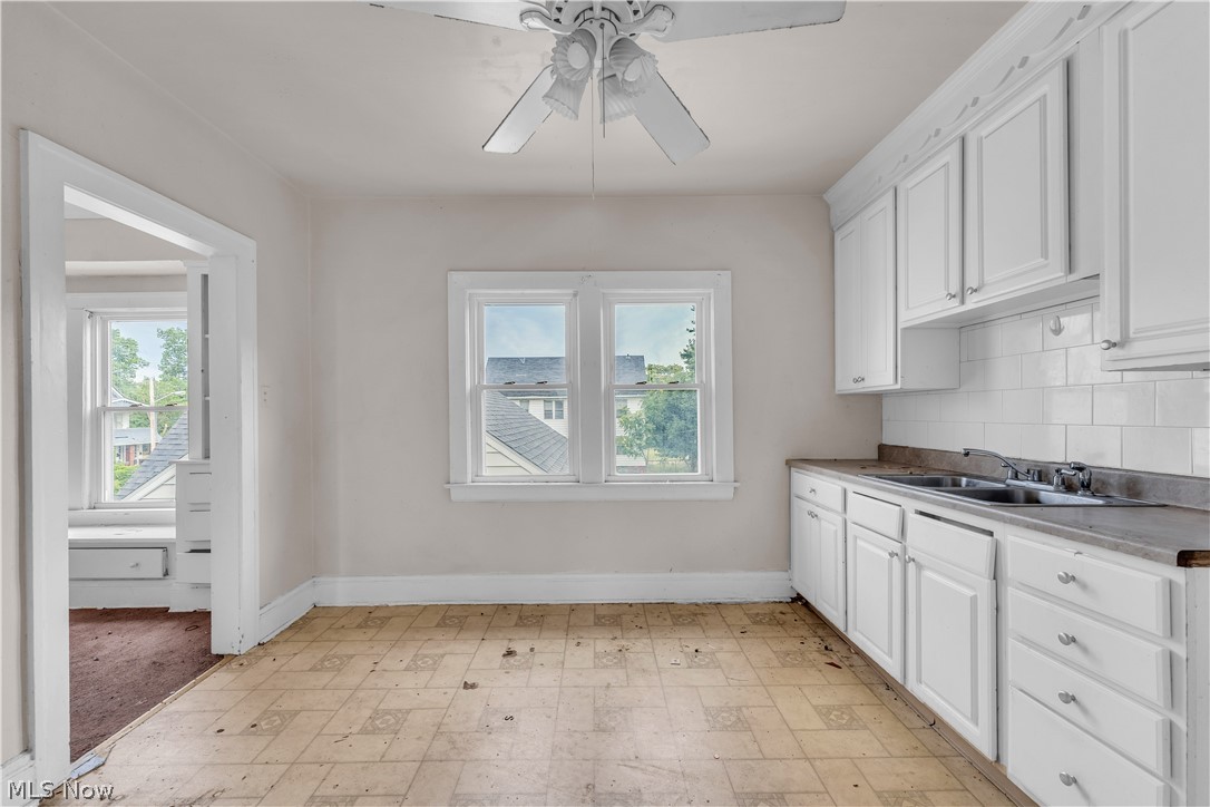 3713 Menlo Road Cleveland, OH 44120 - Photo 18 of 26 Kitchen featuring white cabinetry, ceiling fan, decorative backsplash, sink, and light tile patterned floors