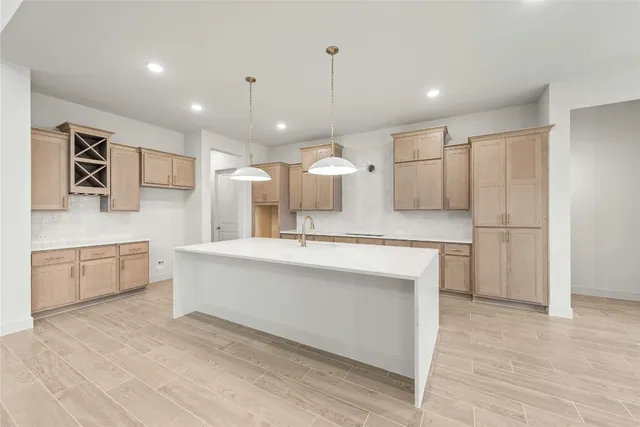 a large white kitchen with a refrigerator a kitchen island a sink and white cabinets