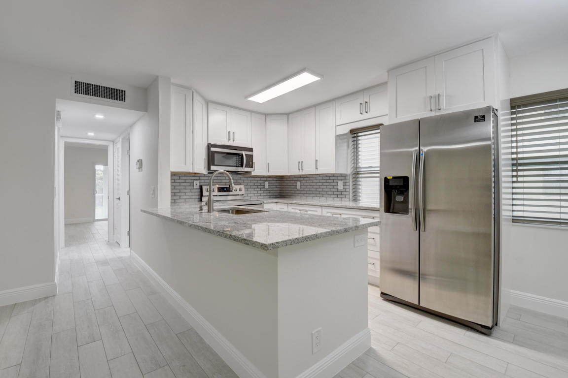76 Flanders B Delray Beach, FL 33484 - Photo 1 of 35 a kitchen with kitchen island granite countertop a refrigerator a sink a stove a microwave and island