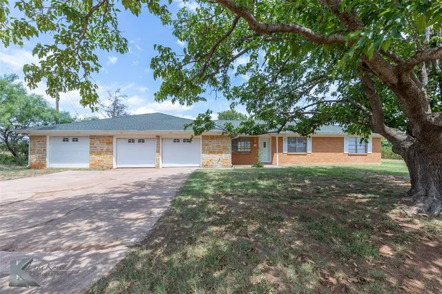 front view of a house with a yard and an trees