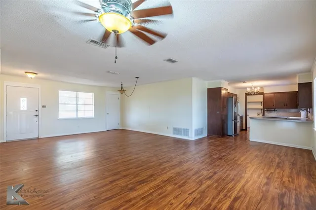 a view of an empty room with window and wooden floor