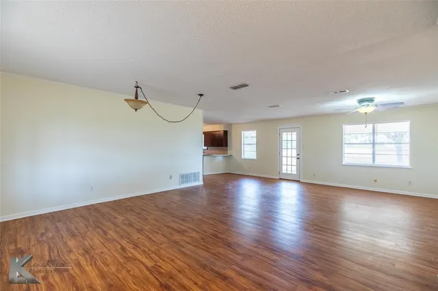 a view of empty room with wooden floor and fan