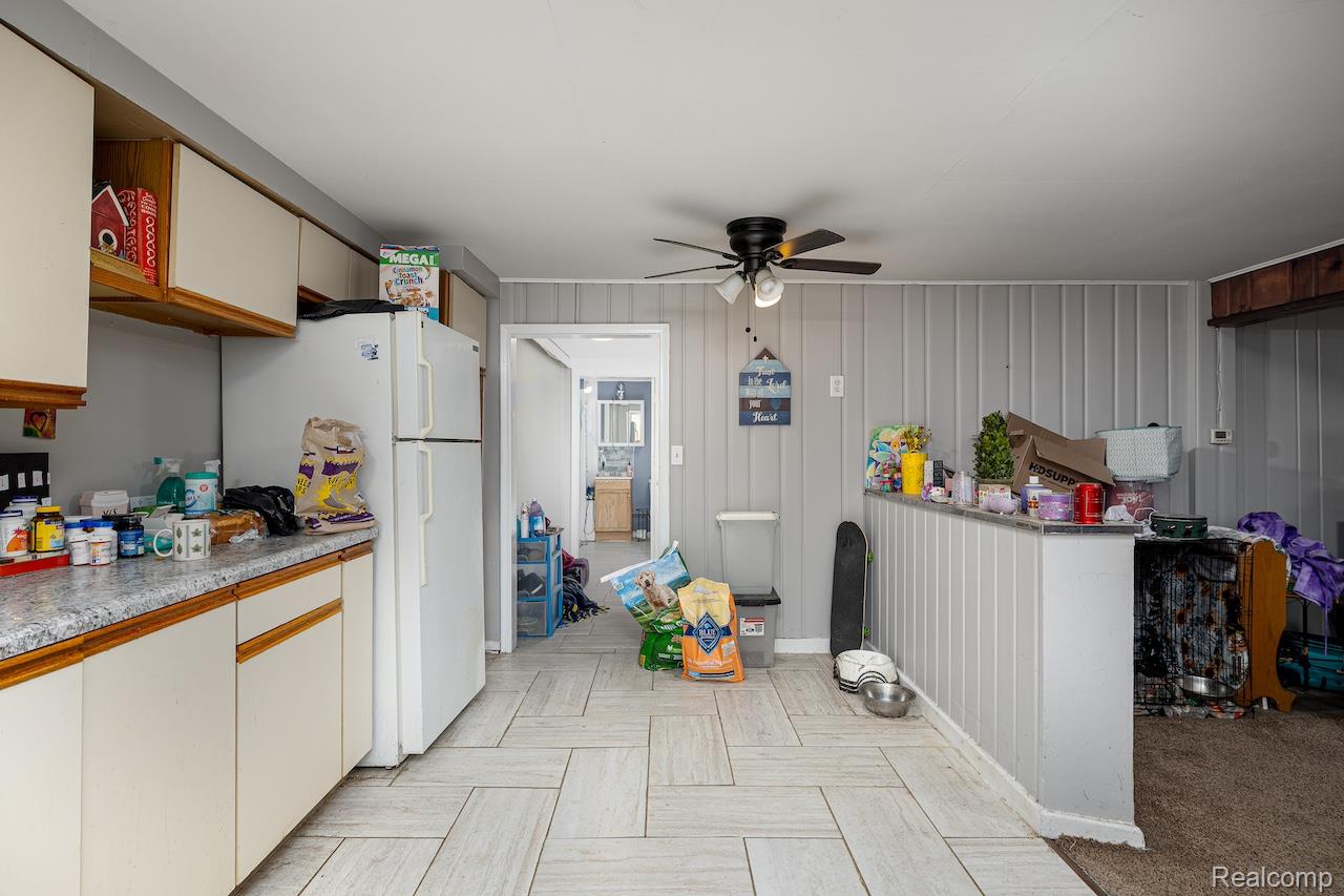 8595 Orchard Road Pinckney, MI 48169 - Photo 20 of 25 Tile flooring with a herringbone pattern, cream cabinetry, a white refrigerator, and a ceiling fan with integrated lighting