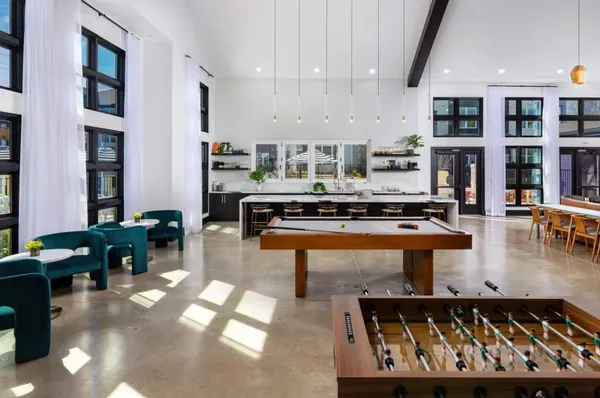 a living room with stainless steel appliances furniture a rug and a kitchen view