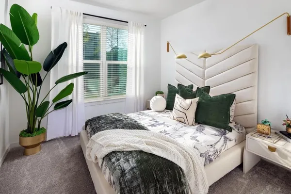 a bed sitting in a bedroom next to a window with potted plant