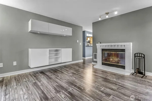 a view of an empty room with wooden floor fireplace and a window