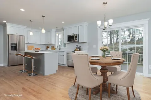 a dining room with kitchen island stainless steel appliances furniture a window and kitchen view