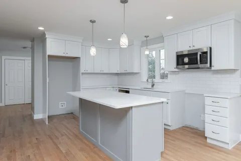 a kitchen with a sink a microwave and wooden floor