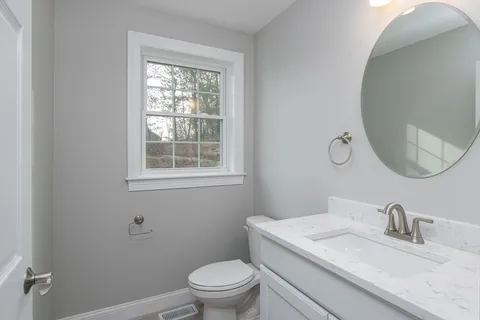 a bathroom with a granite countertop toilet a sink and a mirror
