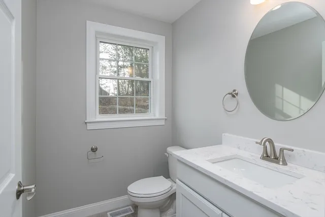 a bathroom with a granite countertop toilet a sink and a mirror
