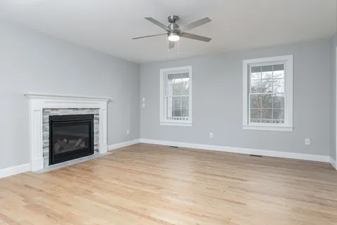 a view of empty room with wooden floor and a fireplace