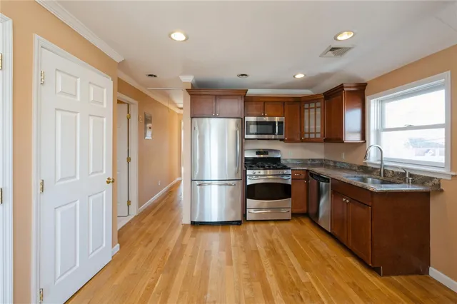 a kitchen with kitchen island wooden floors appliances and window