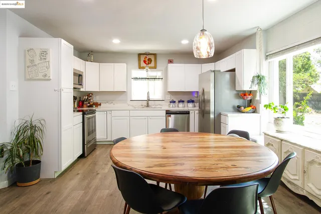 a kitchen with stainless steel appliances granite countertop a stove a refrigerator a kitchen island a sink dishwasher and white cabinets with wooden floor