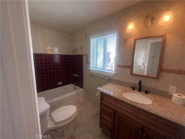 a bathroom with a granite countertop toilet sink and mirror