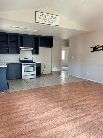 a view of kitchen with stainless steel appliances wooden floor and living room view