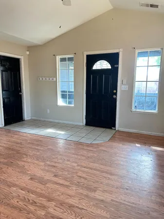 an empty room with wooden floor and windows