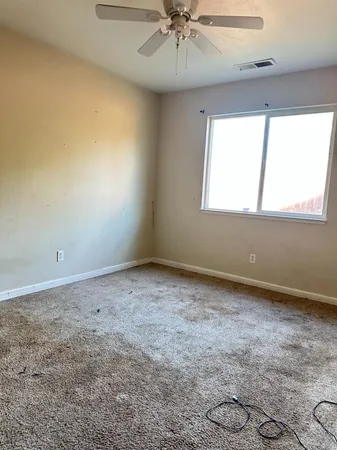 an empty room with a window and ceiling fan