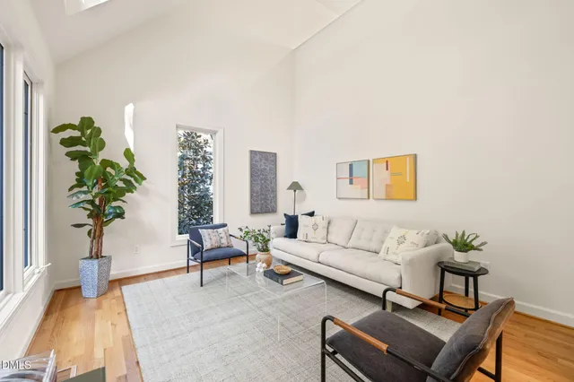 a living room with furniture large windows and wooden floor