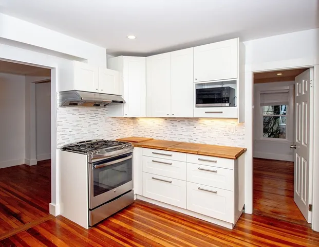 a kitchen with granite countertop wooden floor stainless steel appliances and sink