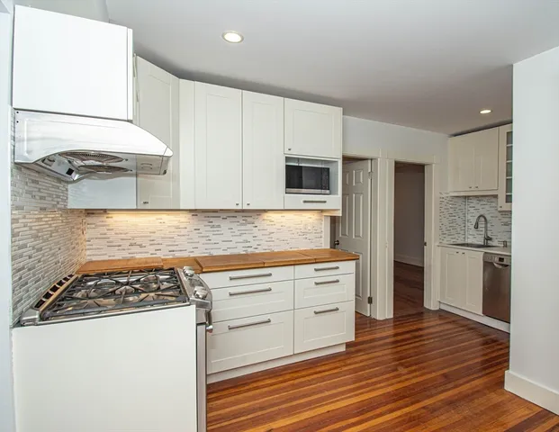 a kitchen with cabinets appliances and wooden floor