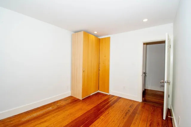 a view of empty room with wooden floor and closet